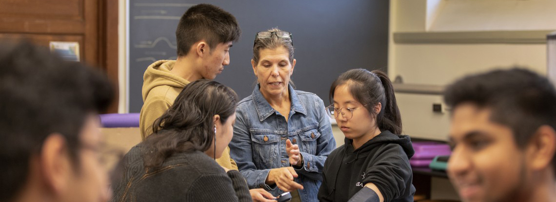 A female Cornell professor works with her students in the classroom