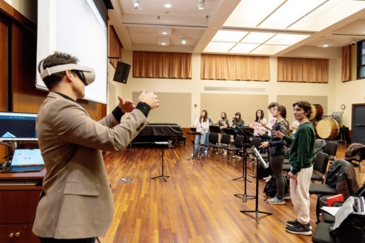 Professor wearing VR headset shows students how to conduct in extended reality