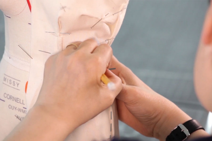 Close-up of hands draping fabric on a dress making form
